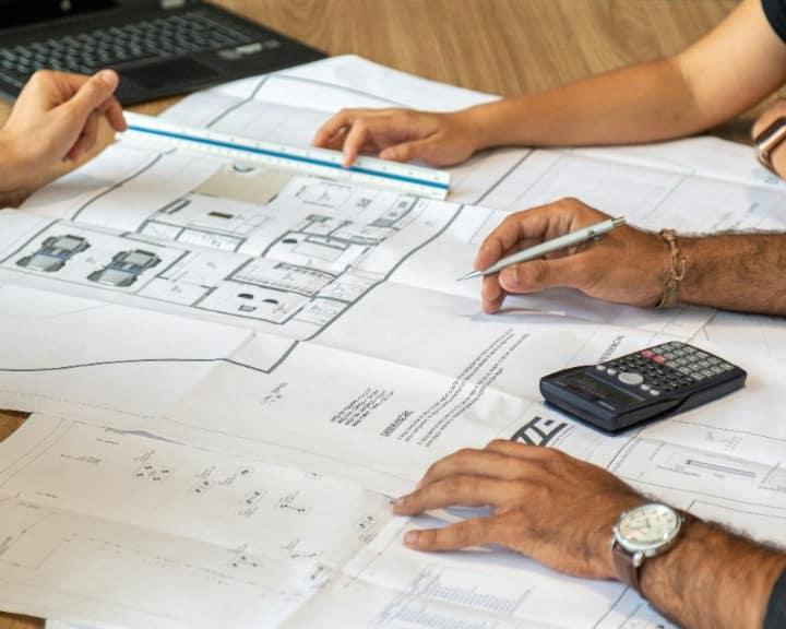 Architects reviewing building blueprints with a ruler and pen
